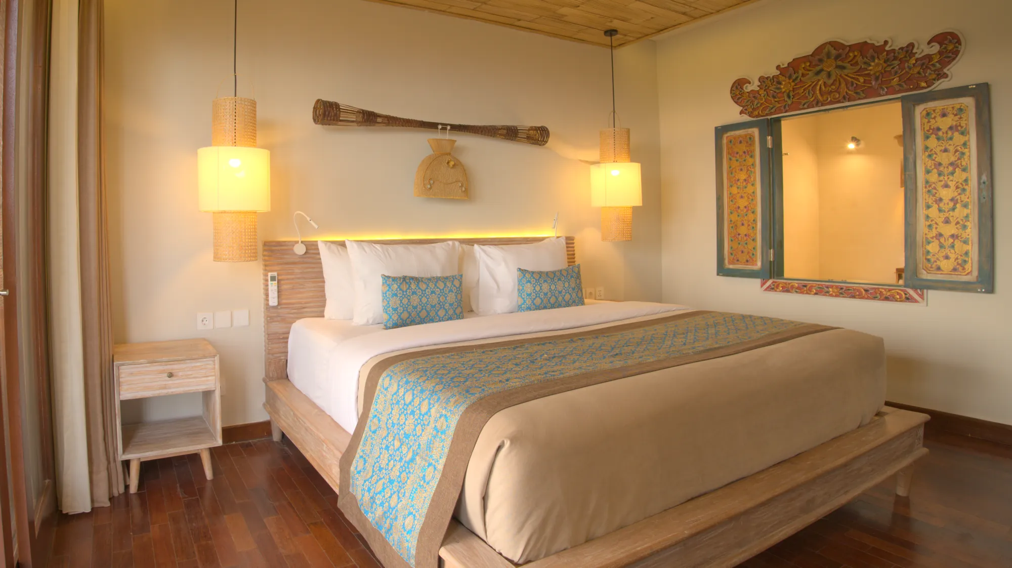 Bedroom with a king bed, a carved wooden window and warm lighting under a bamboo ceiling
