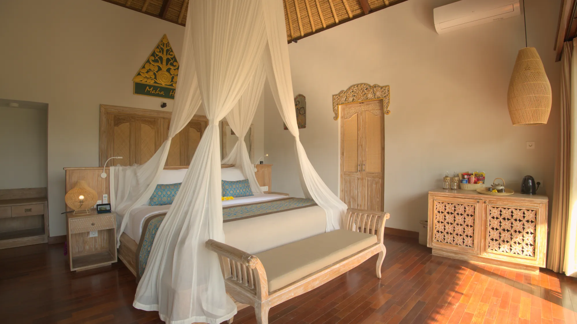 Bedroom with a canopy bed, a bench and a carved wooden cabinet under a high thatched ceiling