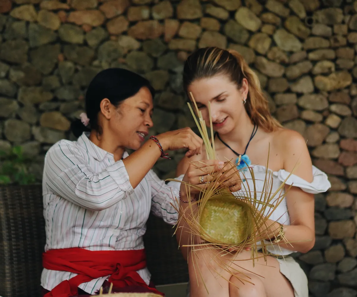 Two women weaving a basket from bamboo strips