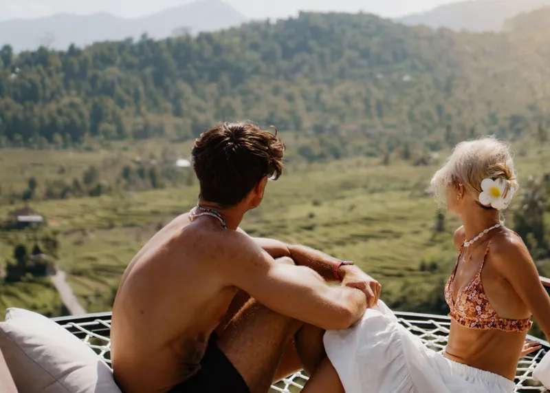 Couple sitting together on a daybed looking over green hills and rice terraces